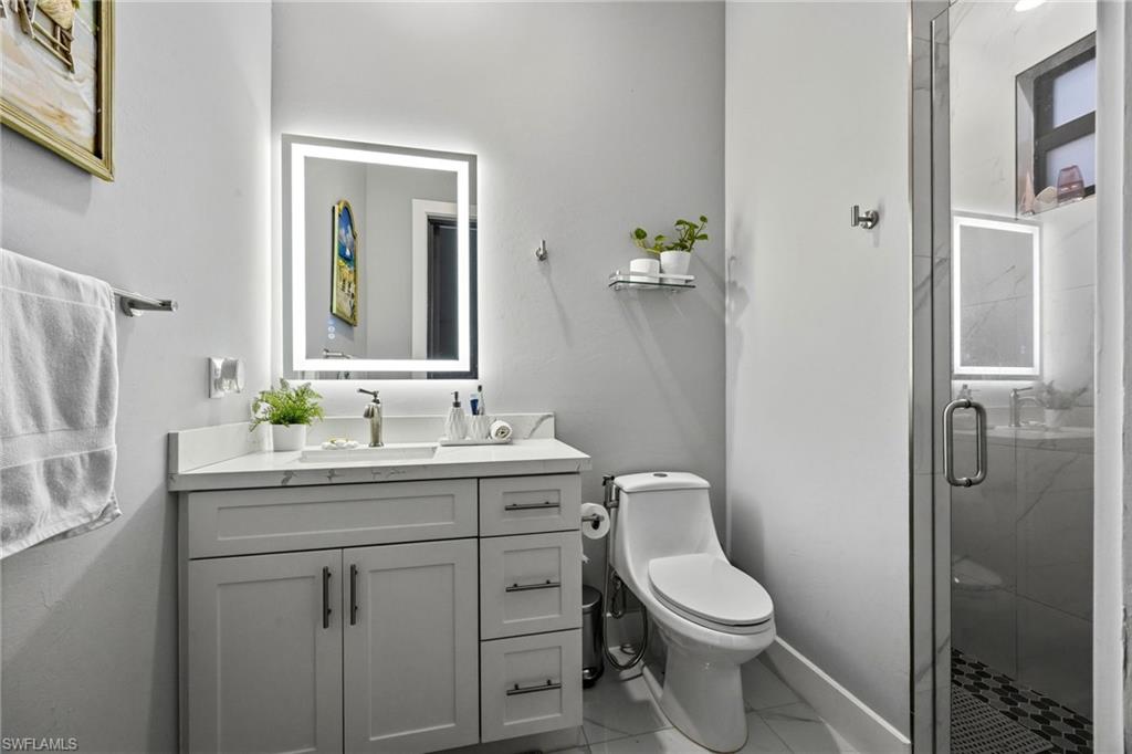Contemporary bathroom featuring a single vanity with a white countertop and light gray cabinetry