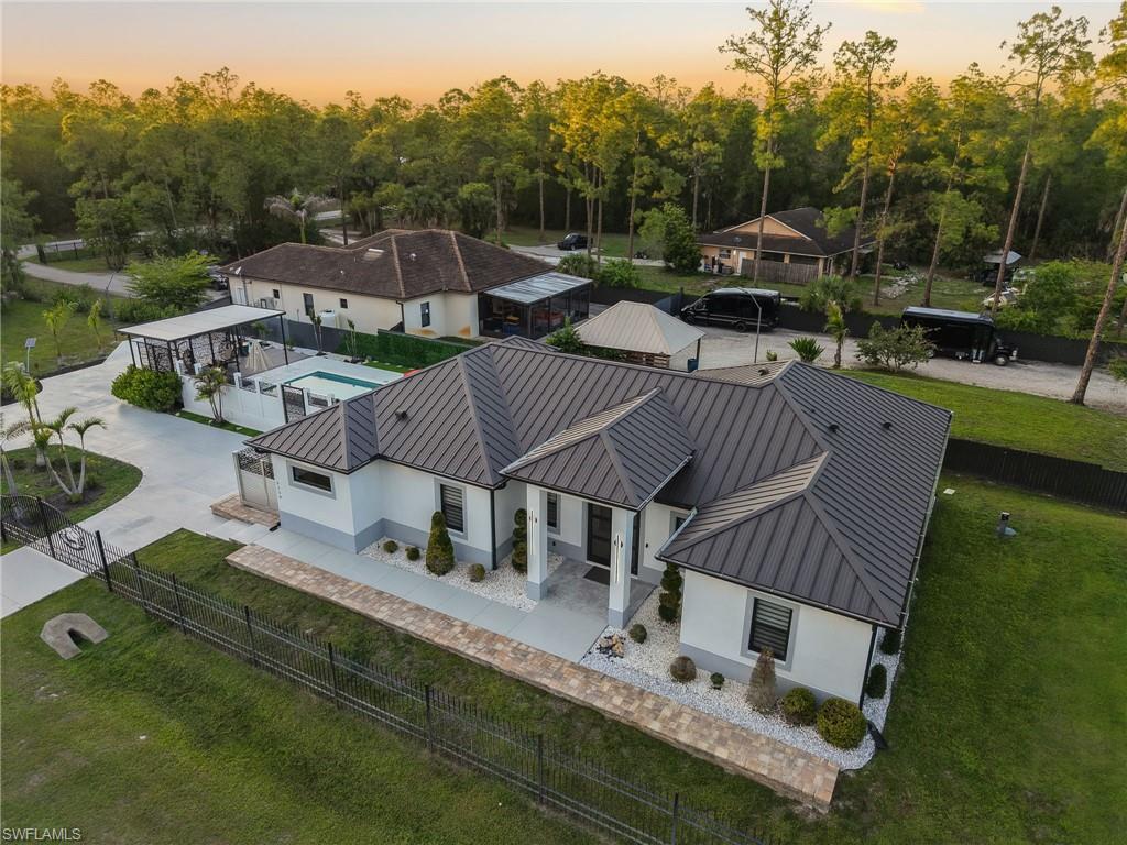 Contemporary residence featuring a dark metal roof, white exterior walls, and a light gray base