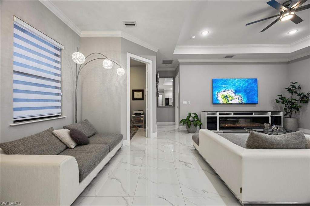 Spacious living area featuring polished tile flooring and crown molding