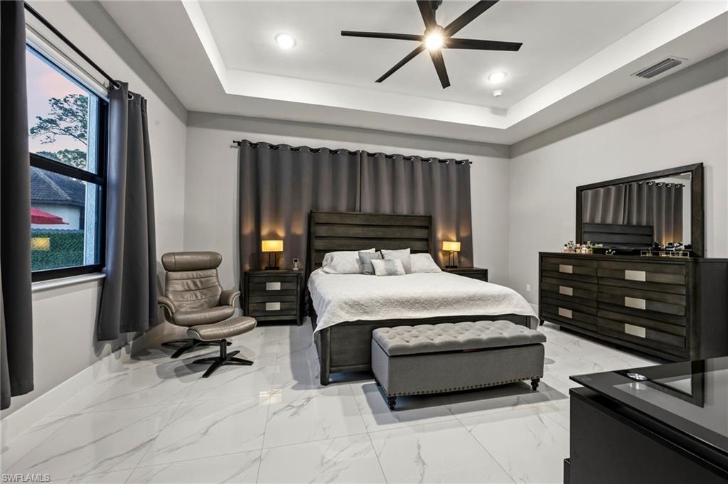 Primary bedroom featuring recessed lighting, a tray ceiling, and a contemporary ceiling fan