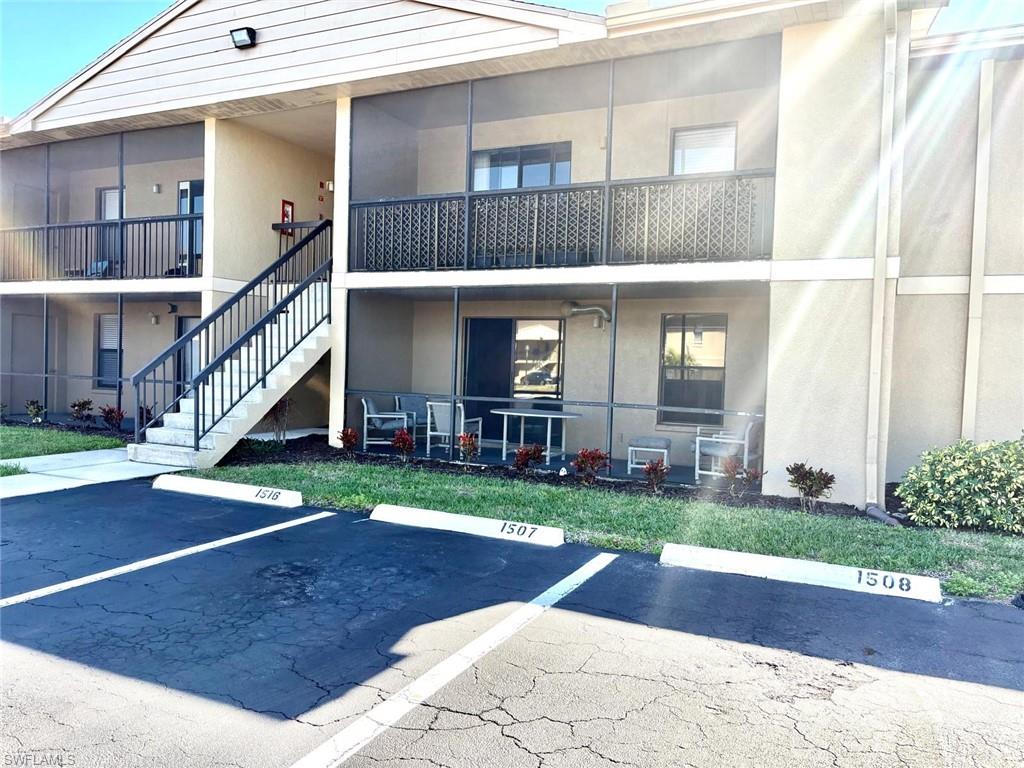 View of property with stairs and uncovered parking