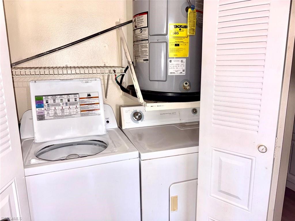 Laundry room with water heater, separate washer and dryer, and a textured wall