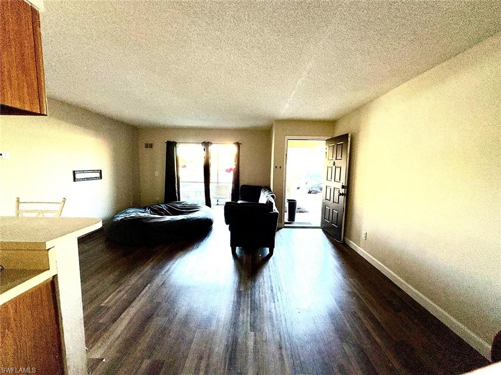 Living area with a textured ceiling and dark wood-type flooring