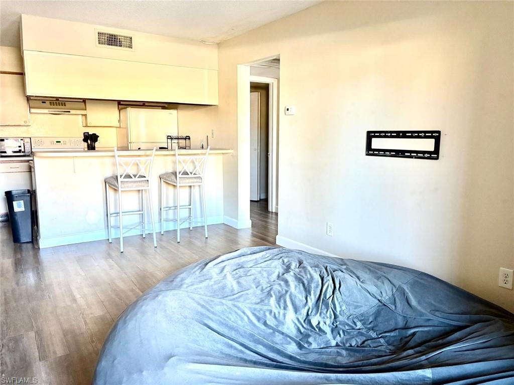 Bedroom with light wood-style floors, freestanding refrigerator, and a closet