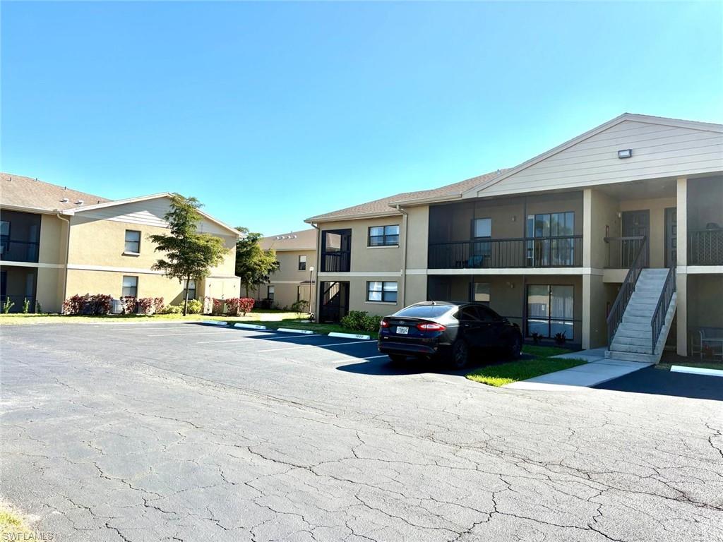 View of property with uncovered parking and stairway
