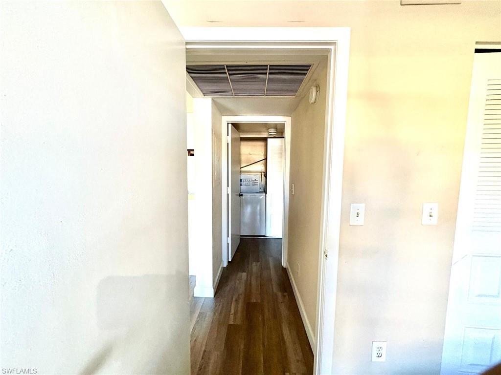 Corridor featuring dark wood finished floors and baseboards