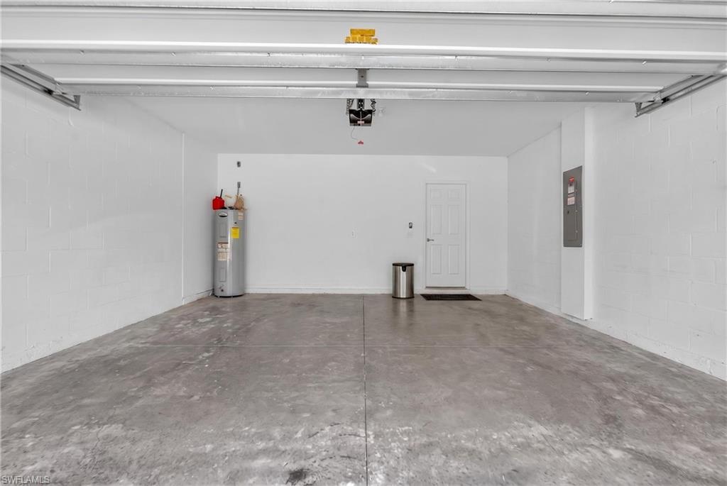 Spacious garage featuring concrete flooring, painted block walls, and a dedicated utility area