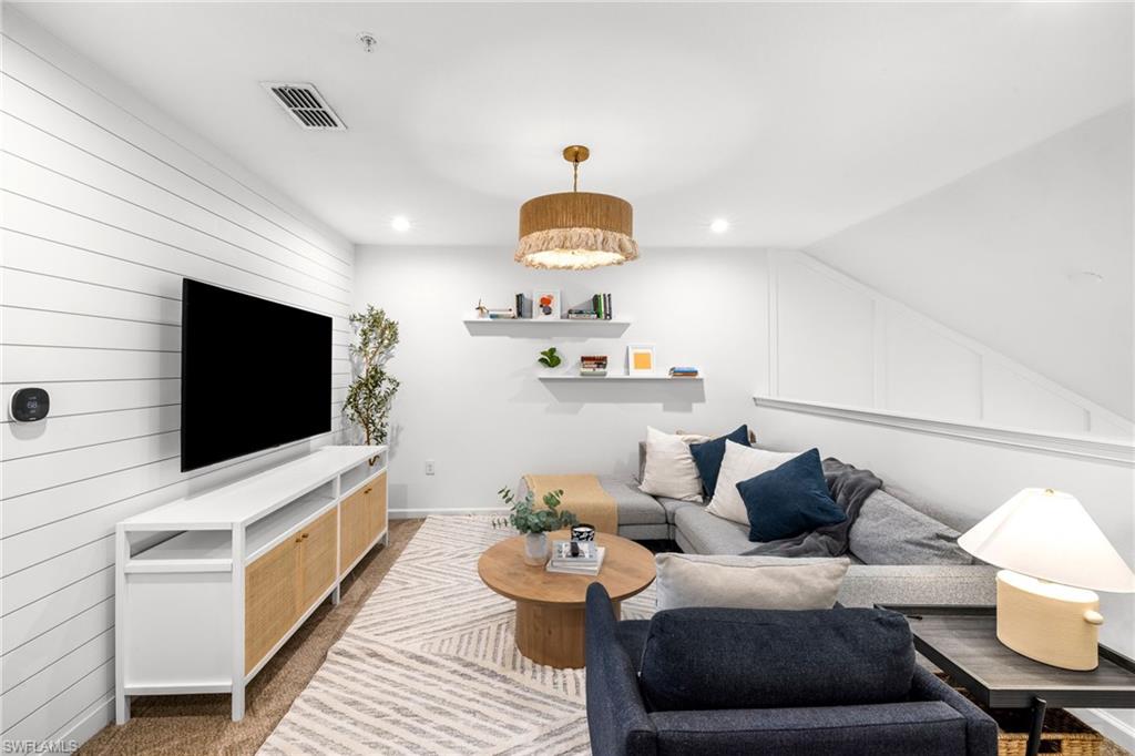 Lower-level living space featuring shiplap accent wall, recessed lighting, and a contemporary ceiling fixture