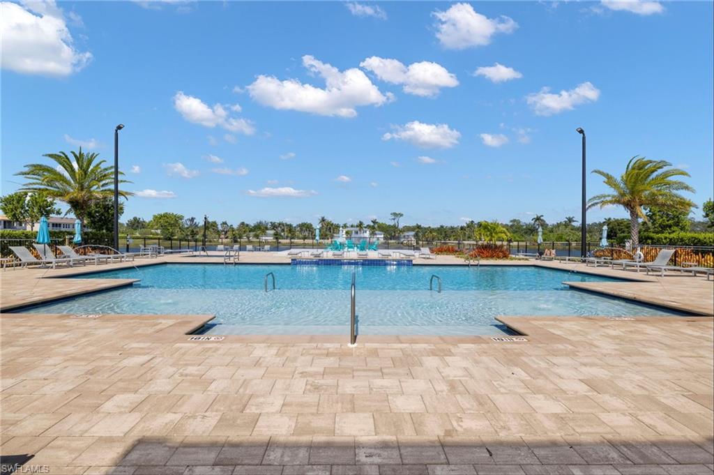 Expansive pool area featuring a large swimming pool, integrated shallow lounging areas, and surrounding paver decking