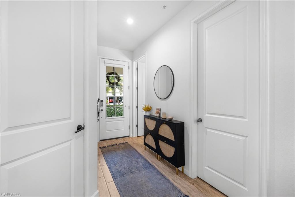 Inviting entryway featuring plank flooring, a single-panel door with transom window, recessed lighting, and a console with a circular mirror