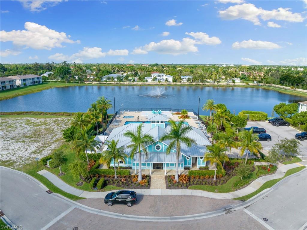 Clubhouse featuring a vibrant turquoise and white exterior, a metal roof, and surrounding palm trees