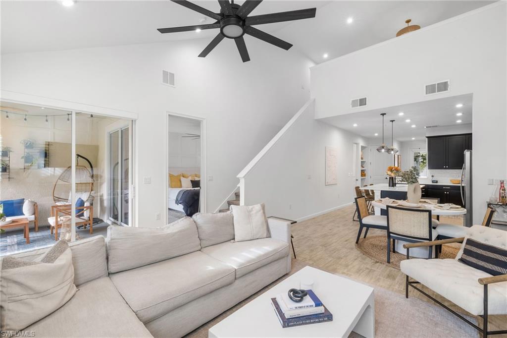 Bright living area featuring vaulted ceilings, a contemporary ceiling fan, and sliding glass doors to a paved outdoor patio