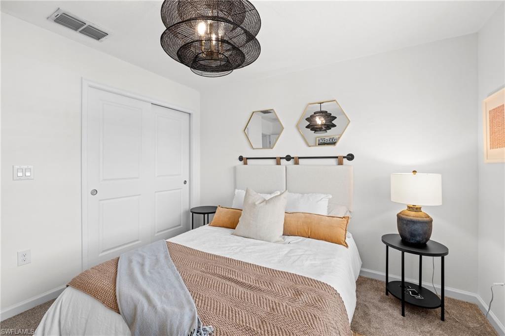Bedroom featuring a contemporary black wire-frame chandelier, white panel closet doors, and light-toned carpeting