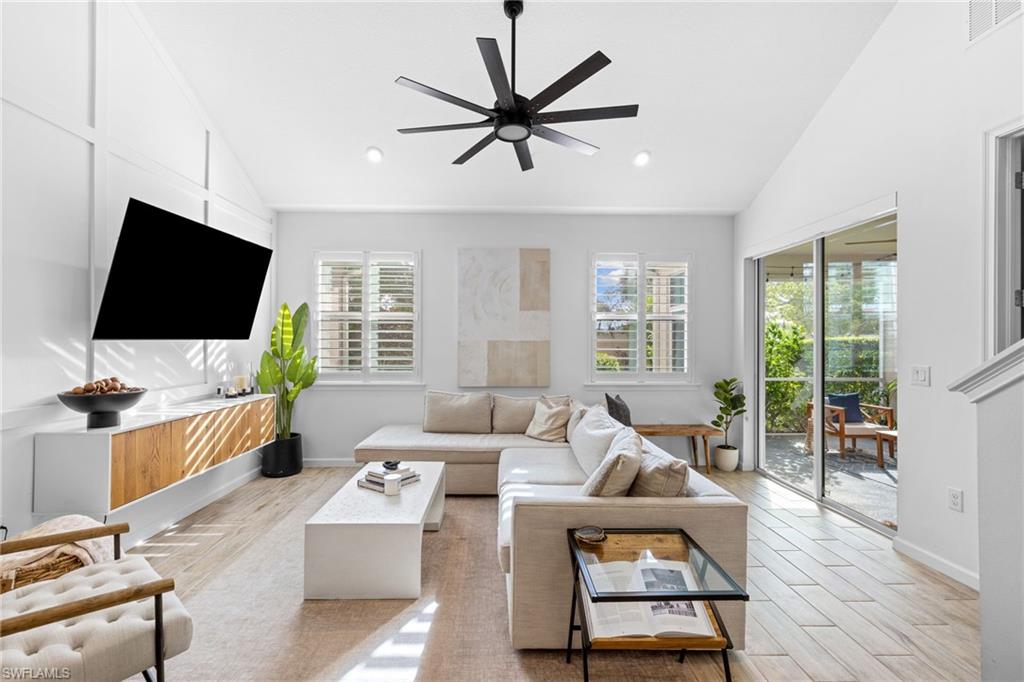 Bright living area featuring vaulted ceilings, a contemporary ceiling fan, and wood-finish flooring