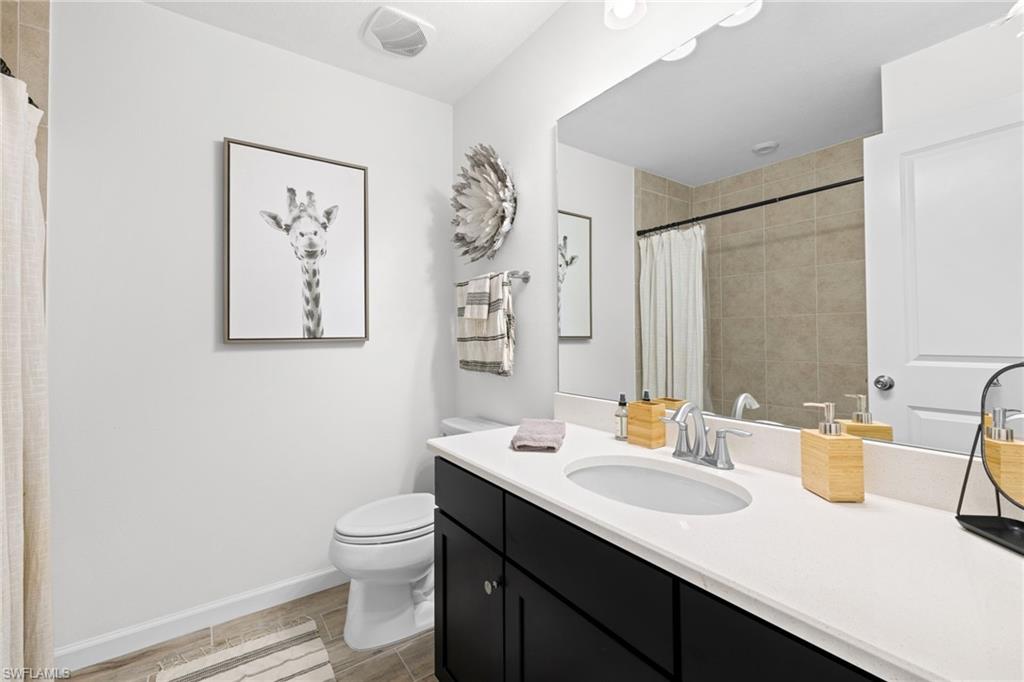 Bathroom featuring a dark wood vanity with a white countertop, an undermount sink, and a large wall mirror