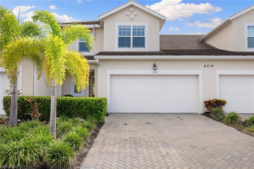 Stucco exterior featuring dual garage doors, a paver driveway, and a tile roof