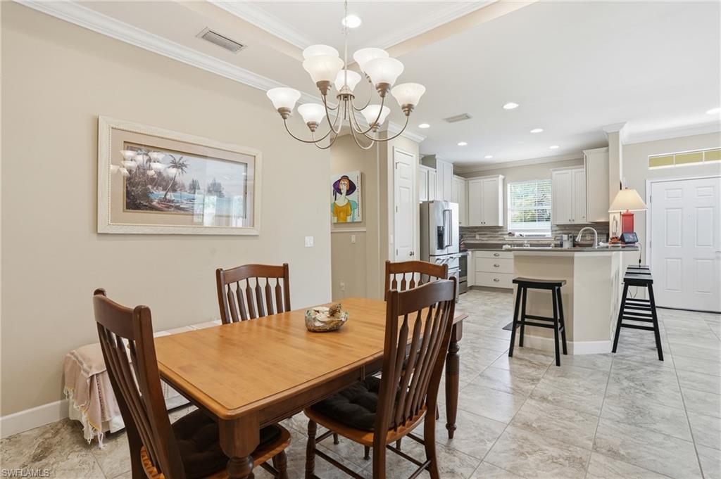 Dining area featuring a contemporary chandelier, crown molding, and tiled flooring