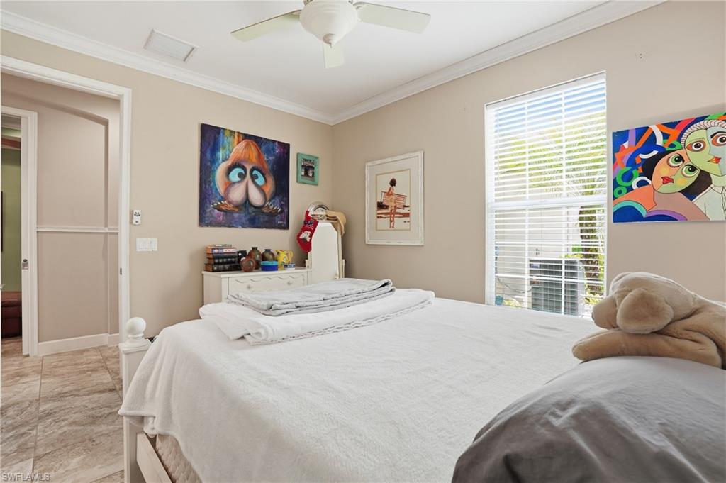 Neutral-toned room featuring crown molding, a ceiling fan, and a window with horizontal blinds