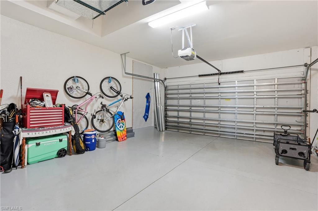 Spacious garage featuring a light gray epoxy floor coating, white painted walls, and a visible garage door opener mechanism