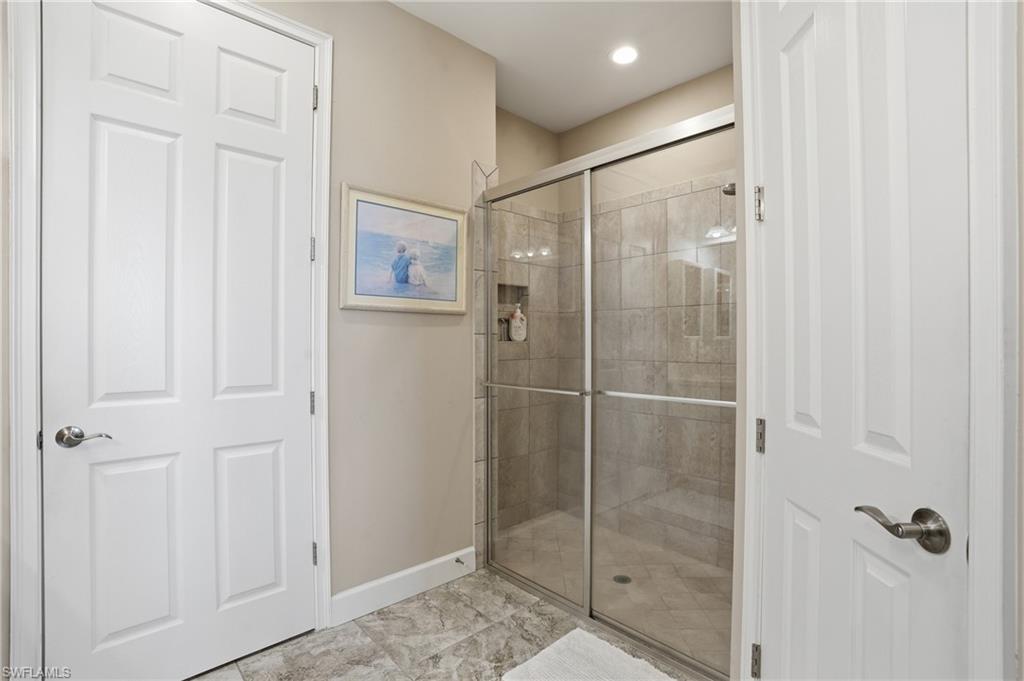 Full shower enclosure featuring a tiled interior, glass sliding doors, and integrated lighting