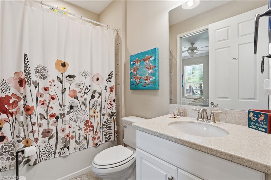 Bathroom featuring a single vanity with a light-colored countertop, an undermount sink, and a chrome-finish faucet