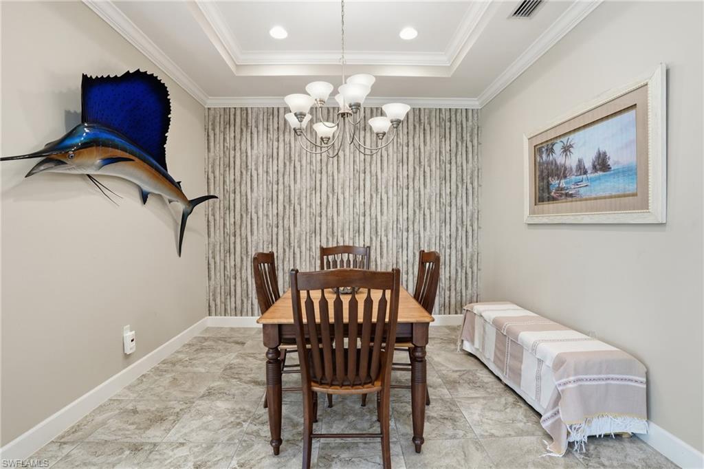 Dining area featuring a tray ceiling with recessed lighting and a chandelier, tiled flooring, and an accent wall with textured wallpaper
