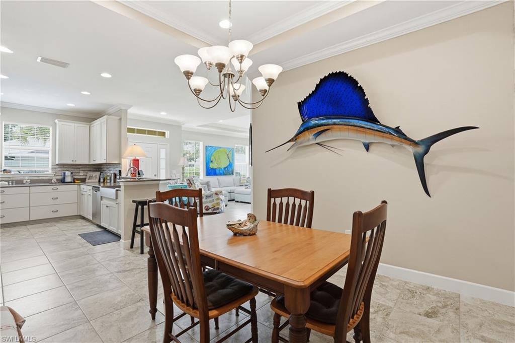 Dining area with a multi-light chandelier and tray ceiling detail