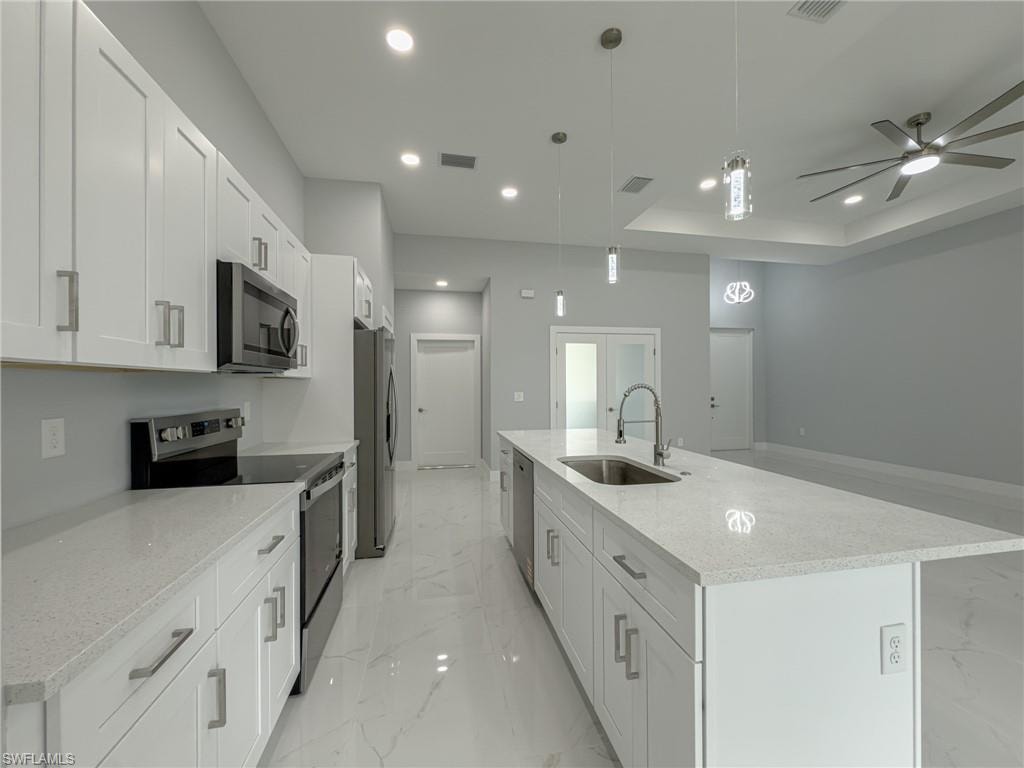 Kitchen featuring a sink, stainless steel appliances, a large island, marble finish floor, and white cabinets