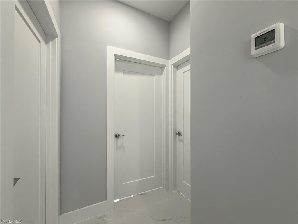 Hallway with marble finish floor and baseboards