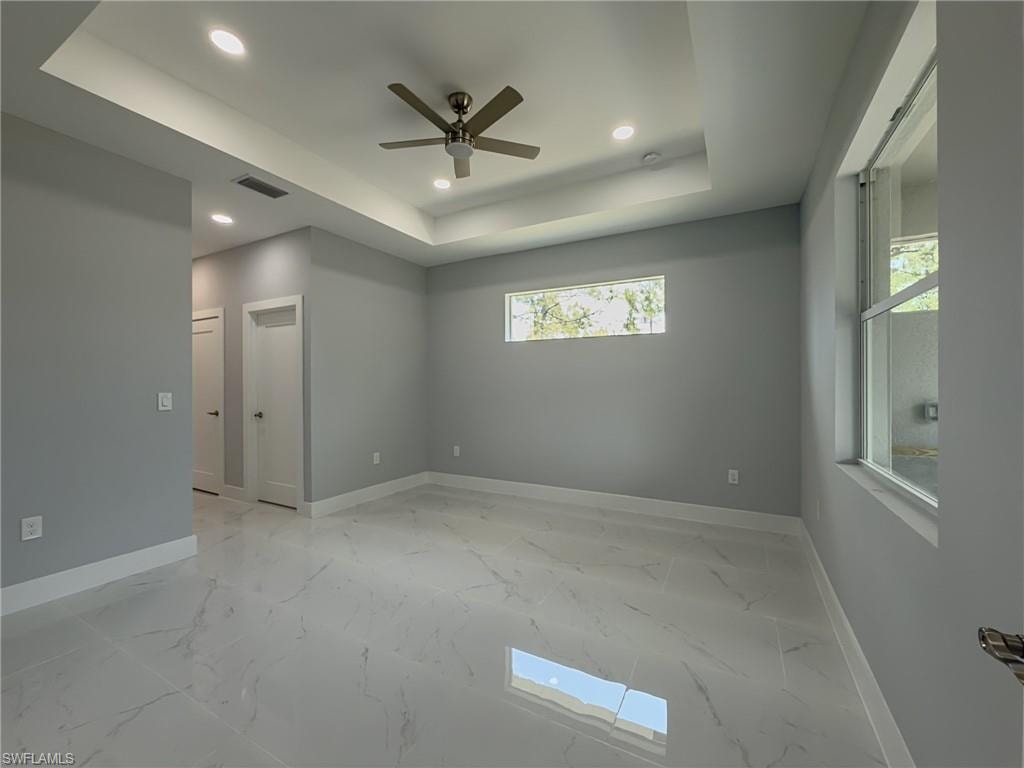 Master bedroom with recessed lighting, ceiling fan, a raised ceiling, visible vents, and baseboards