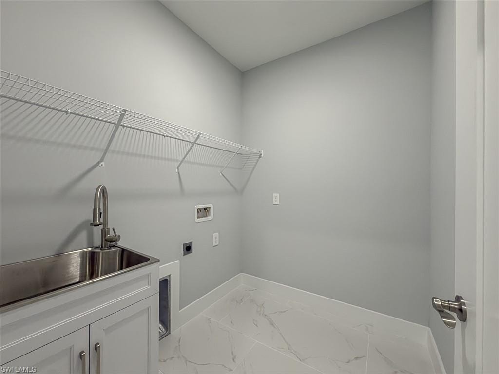 Laundry area with cabinet space, marble finish floor, washer hookup, a sink, and baseboards