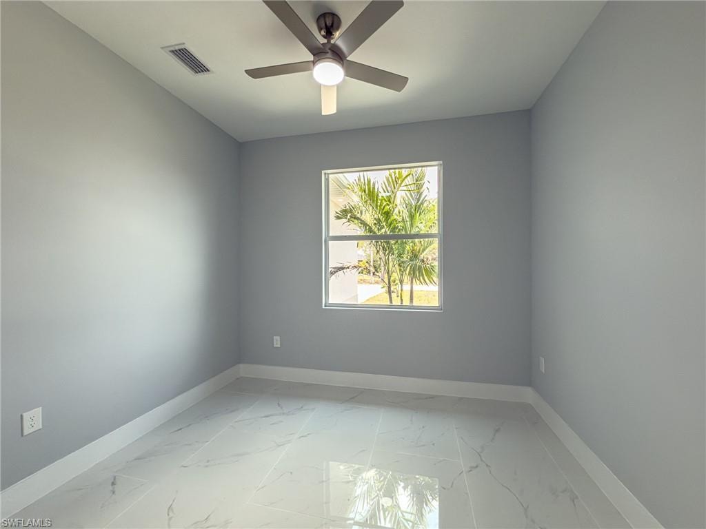 Unfurnished room featuring visible vents, ceiling fan, marble finish floor, and baseboards