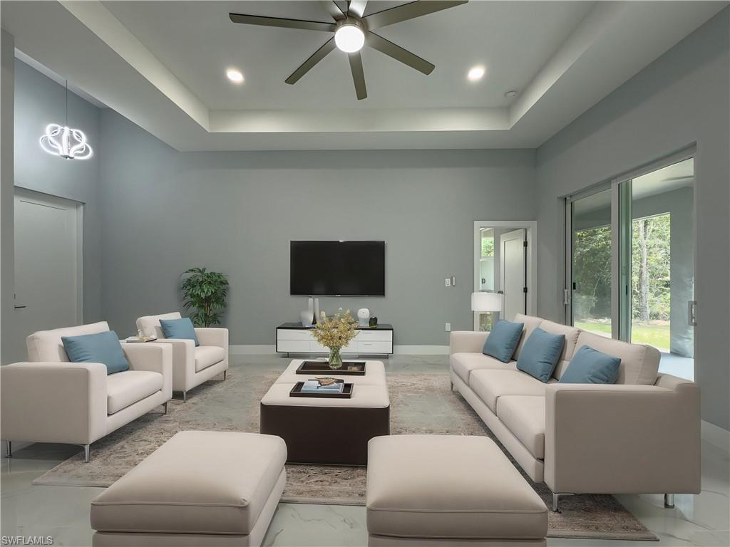 Living area featuring a tray ceiling, a ceiling fan, recessed lighting, and marble finish floor