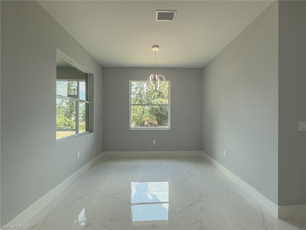 Unfurnished dining area with visible vents, a chandelier, marble finish floor, and baseboards