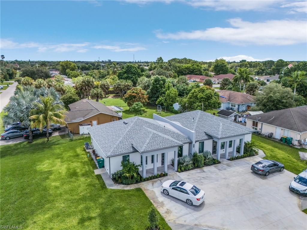Contemporary multi-unit property featuring a clean white stucco exterior, grey asphalt shingle roofs, and a large concrete driveway