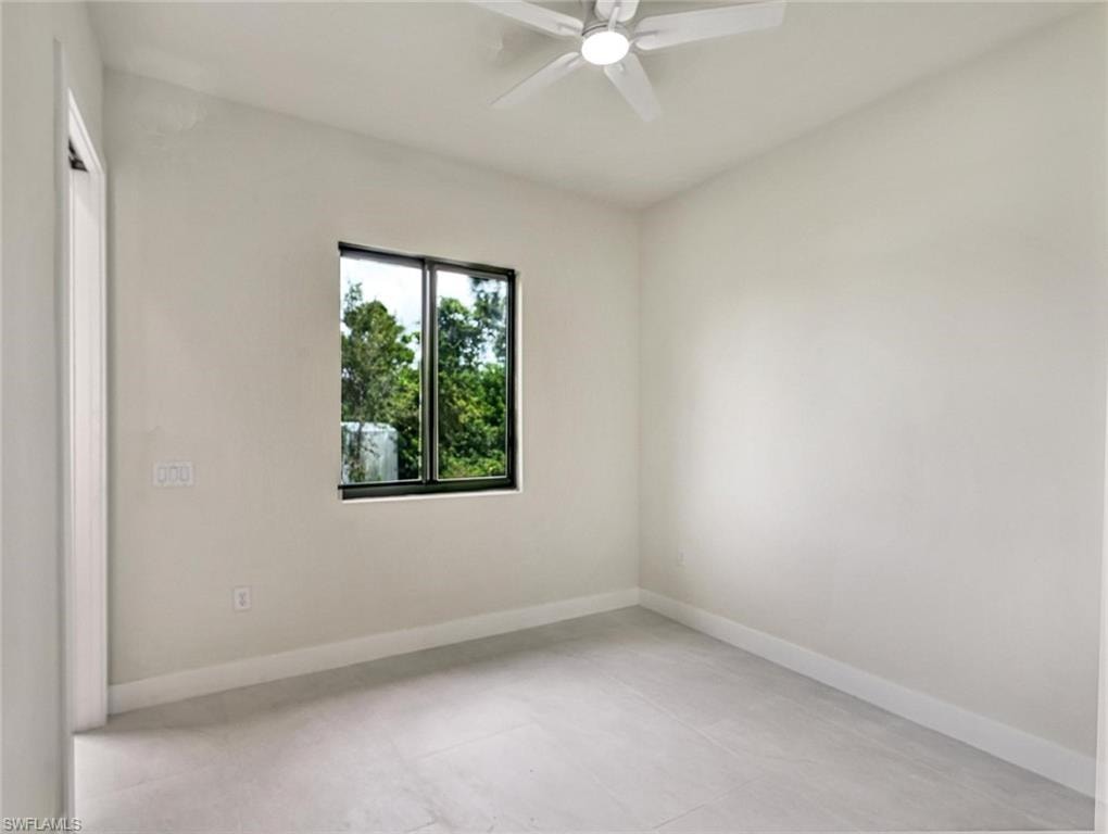 Bright room featuring a window with dark framing, a ceiling fan, light-colored walls, and tile flooring