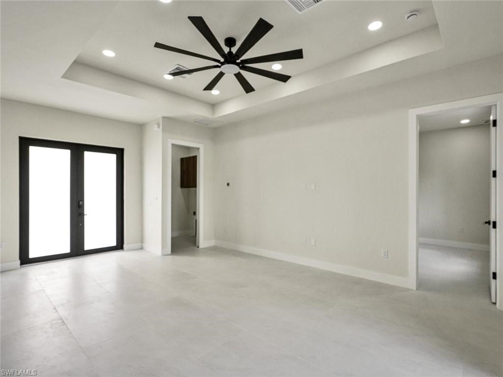Spacious room featuring light-toned tile flooring, a tray ceiling with recessed lighting, and a modern ceiling fan