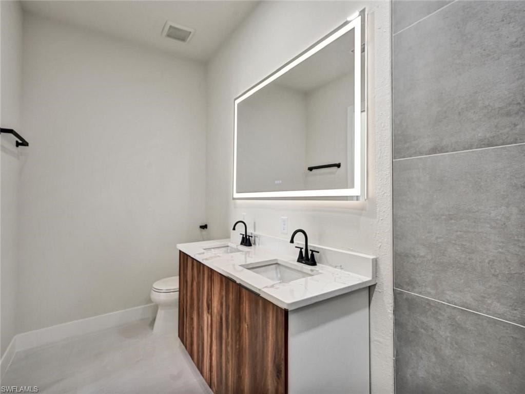 Modern bathroom featuring a dual vanity with wood-finish cabinetry, white countertop, and integrated sinks