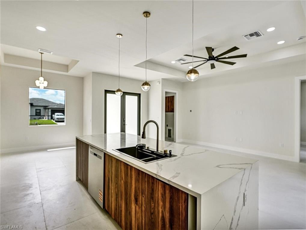 Kitchen island featuring a waterfall-edge countertop, undermount sink with a gooseneck faucet, integrated dishwasher, and wood-finish cabinetry
