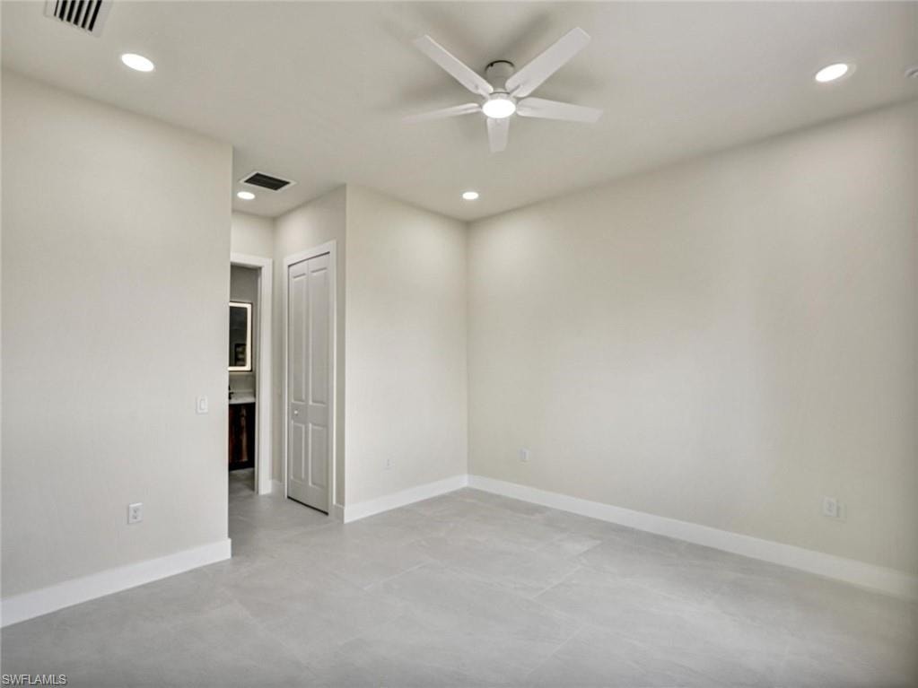 Spacious room featuring light-toned walls, tile flooring, and a ceiling fan