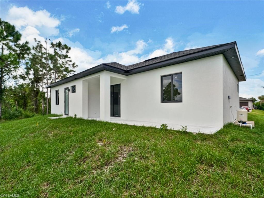 Modern residence with a white stucco exterior, dark-framed windows, and a black shingle roof
