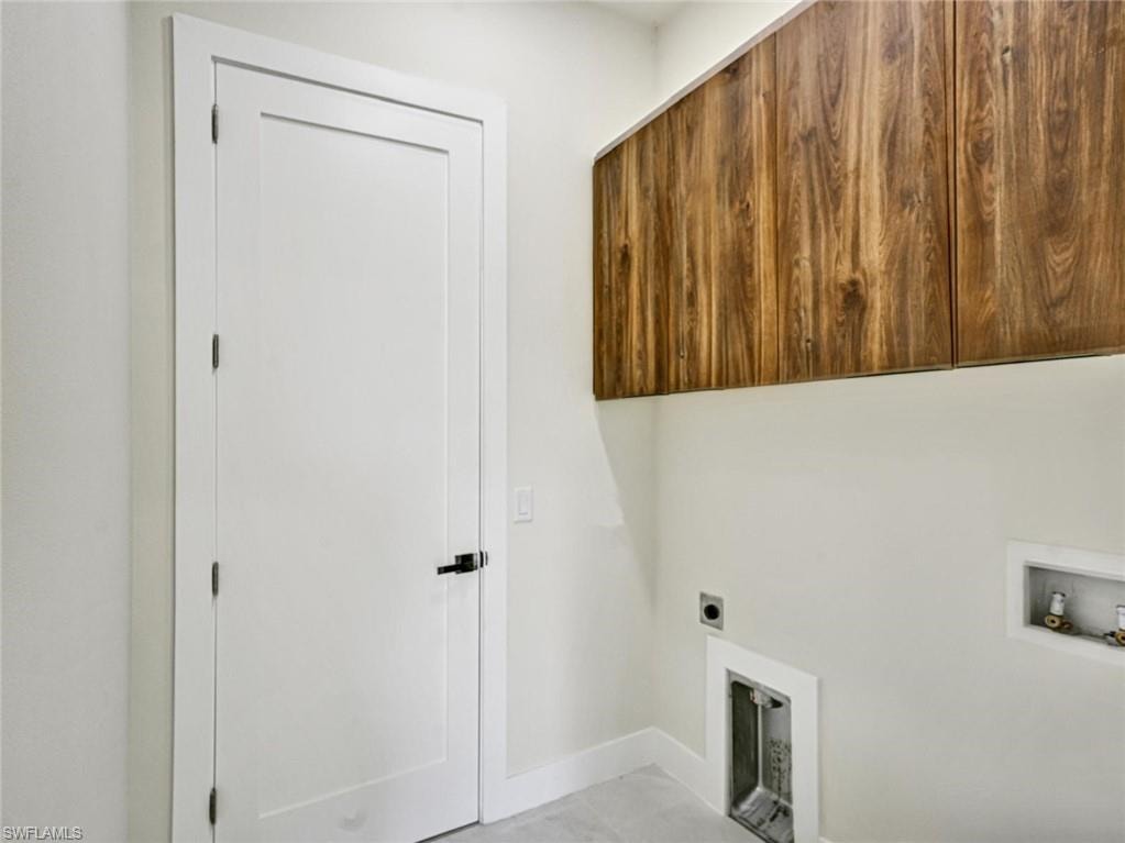 Utility area featuring modern wood-finish cabinetry, a contemporary white door with matte black hardware, and dedicated appliance hookups