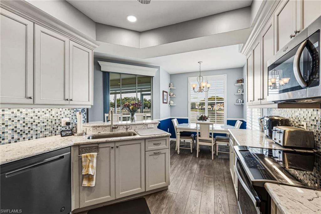 A beautifully redesigned kitchen overlooking the tranquil lake, showcasing exquisite blue-veined granite countertops and matching backsplash, enhanced by ambient under-cabinet lighting, recessed illumination, and a suite of premium stainless steel appliances.