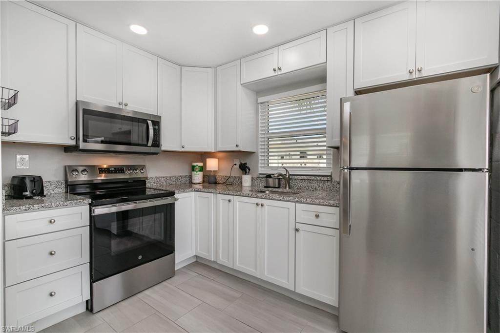 Kitchen features white shaker-style cabinetry and granite counters!