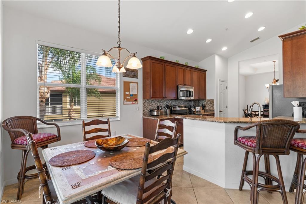 Dining room featuring a chandelier, lofted ceiling, recessed lighting, and light tile patterned flooring