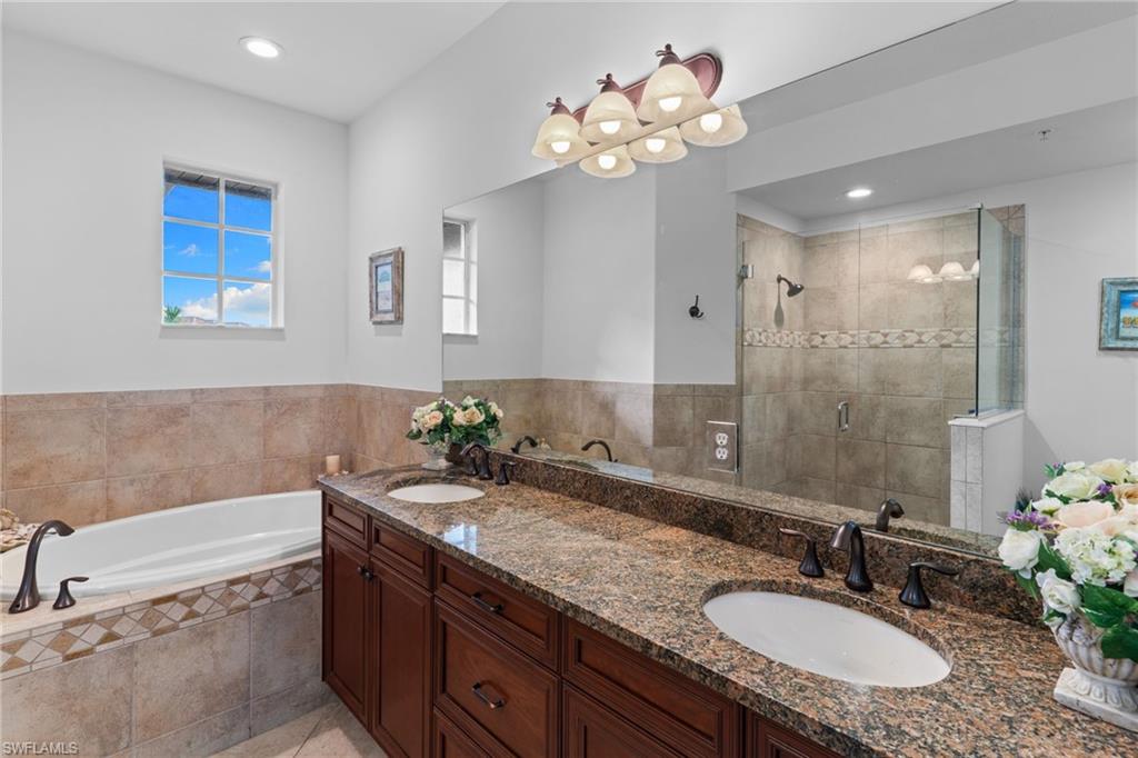 Full bath with double vanity, a shower stall, a garden tub, and recessed lighting