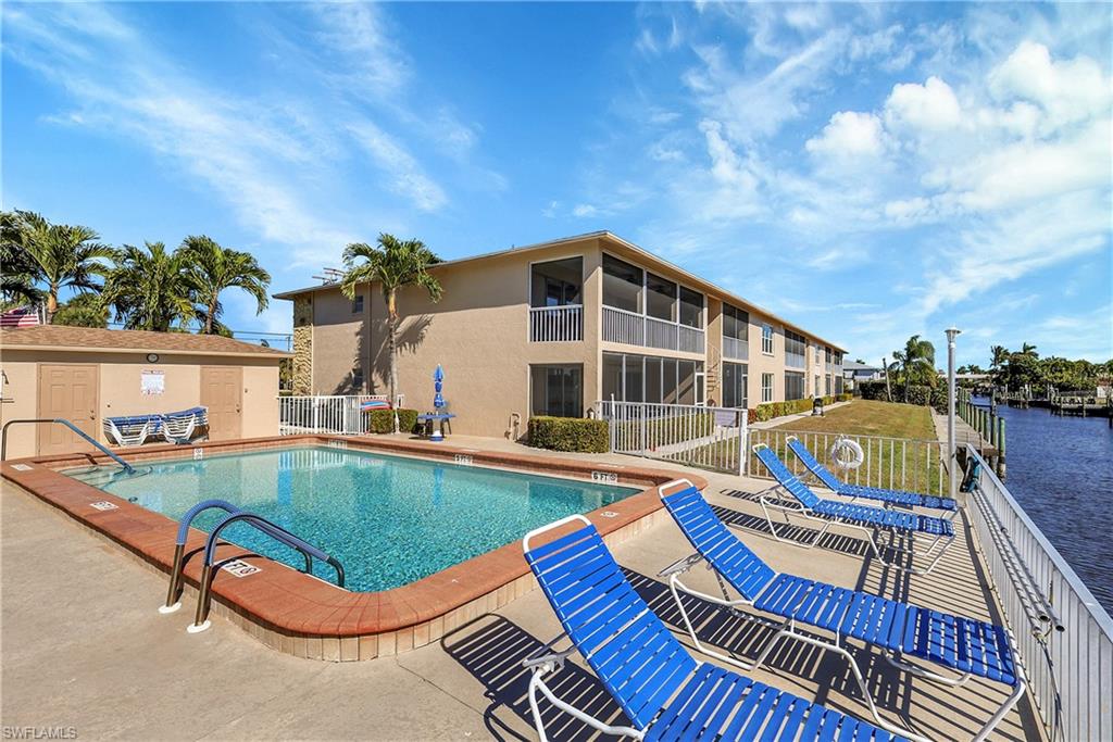 Waterfront heated pool with outdoor shower and lounge chairs.