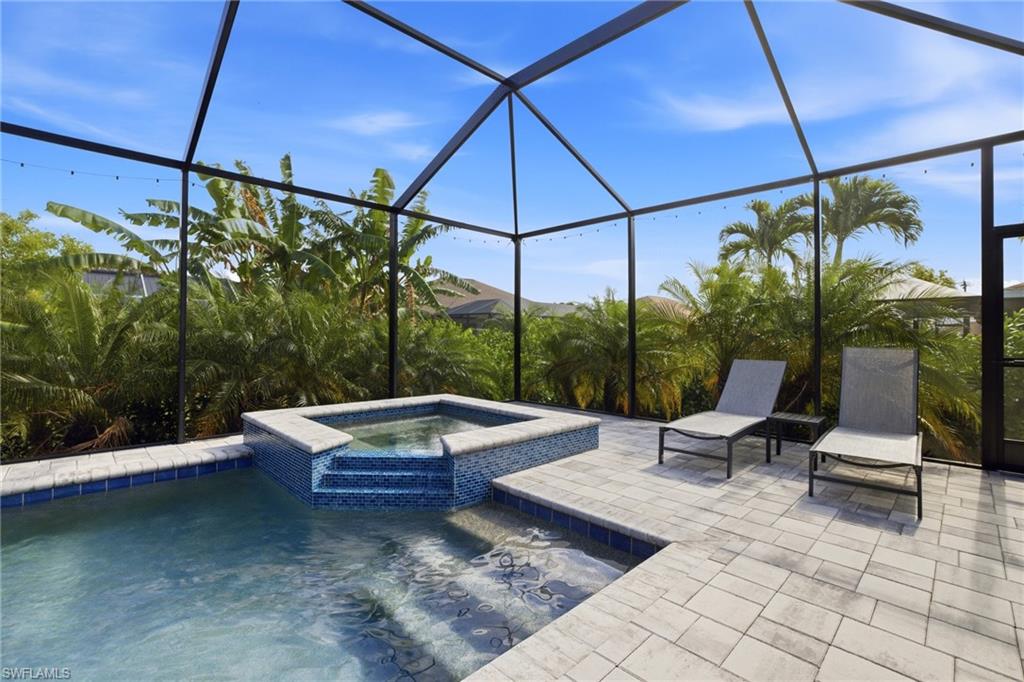 Screened lanai featuring a swimming pool, integrated spa with mosaic tile, and paver decking