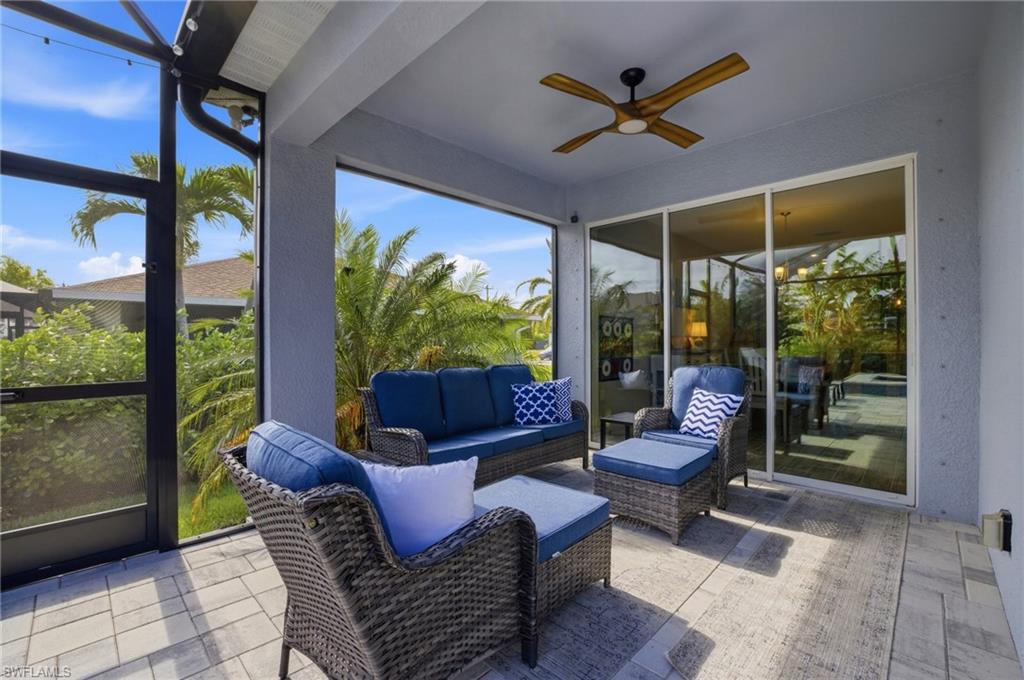 Screened outdoor patio featuring a ceiling fan, sliding glass doors, and paver flooring