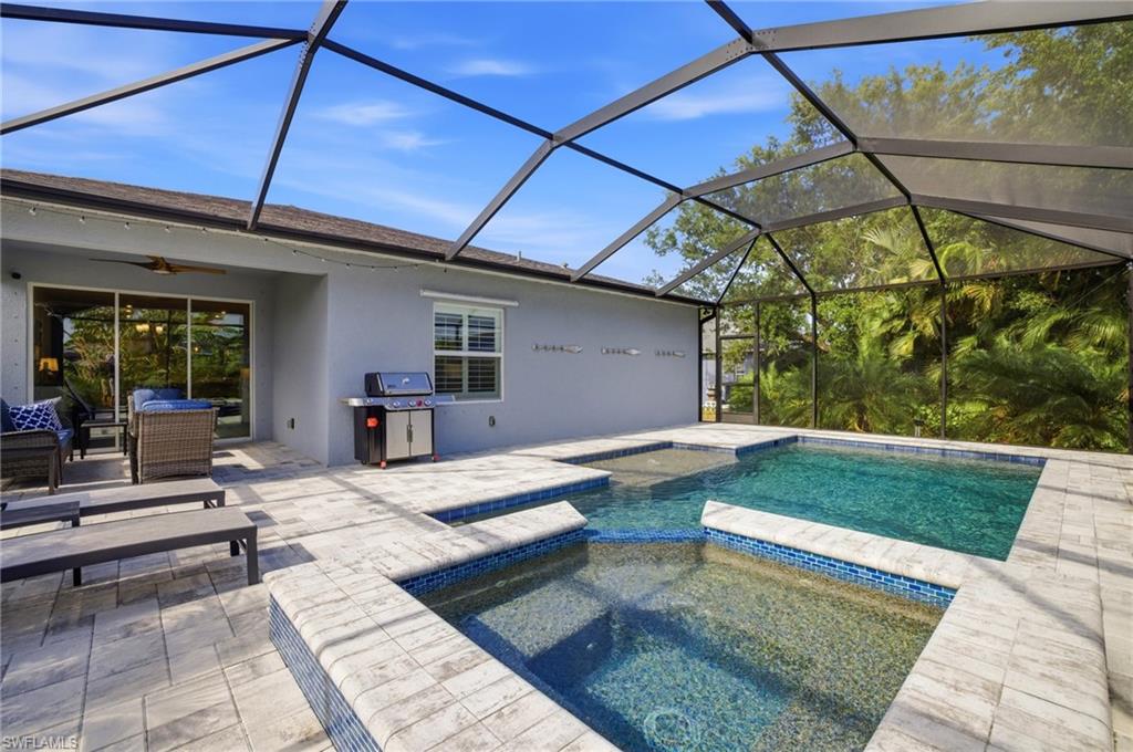 Screened pool and spa area featuring a paver deck, direct access to the interior via sliding glass doors, and privacy landscaping